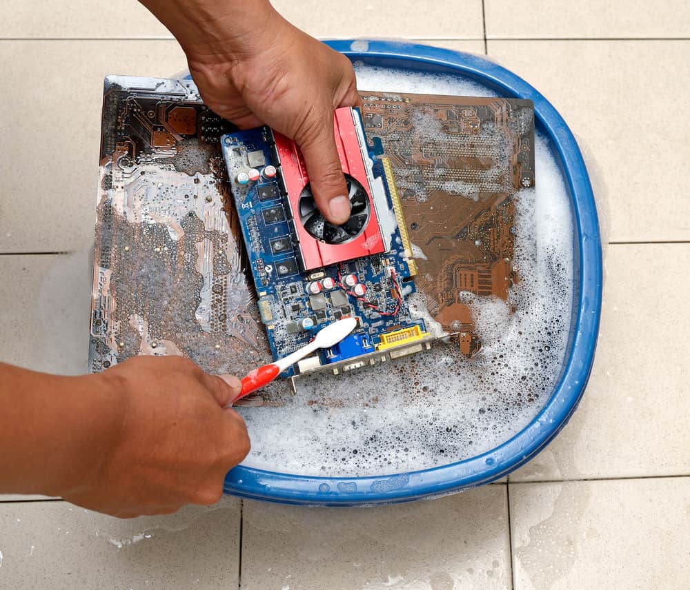 Using a toothbrush and water to remove corrosion from a computer motherboard