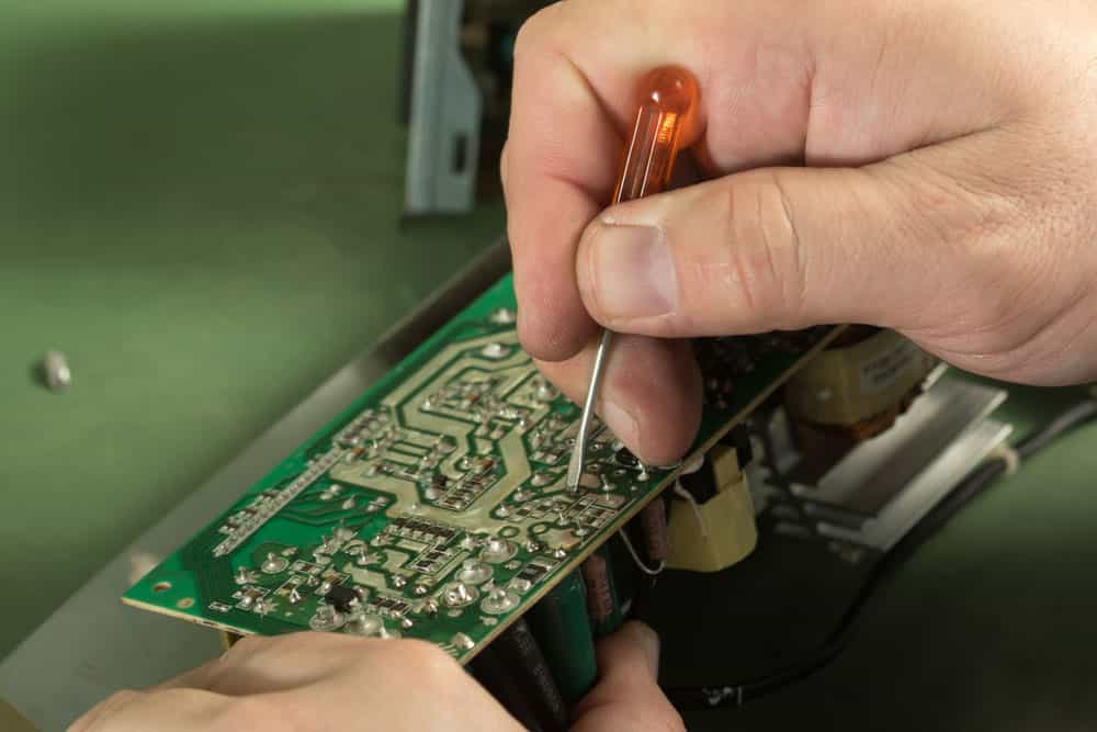 Technician repair circuit board with screwdriver