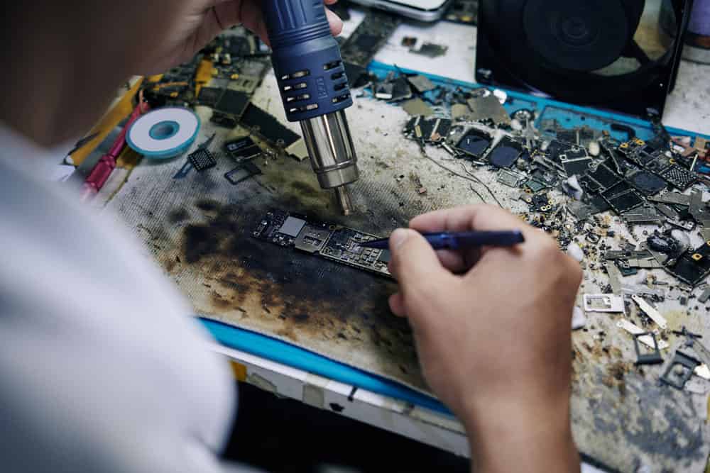 Technician using hot air gun to repair a logic board